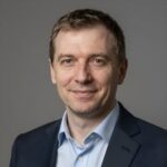 Портрет уверенного российского бизнесмена с дружелюбным взглядом на размытом нейтральном фоне для семинара